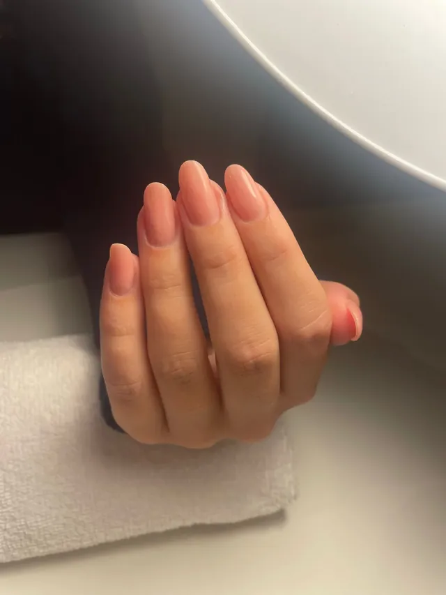 Een hand met roze nagels op een witte handdoek.