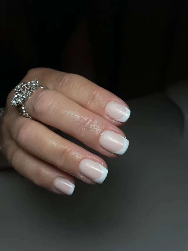 Nagels met een zachte witte french-rand, close-up.