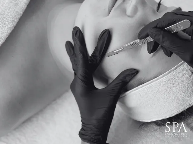 Dermaplaning in zwart-wit: een mesje wordt over de huid van een gezicht geleid.