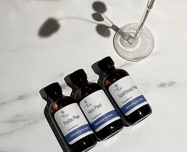 Drie Linder Health peelingflesjes op marmer, naast een glazen schaaltje.