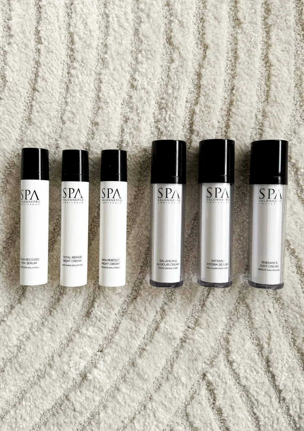 Zes flesjes van SPA SalonnePro op een beige textiel.